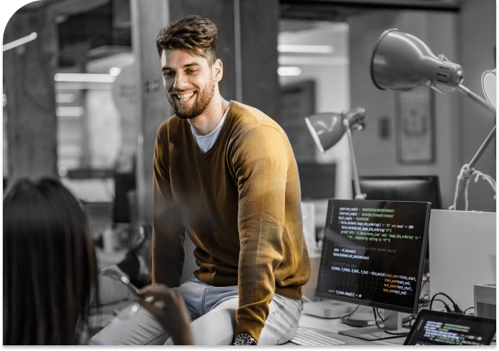 Young software engineer smiling and talking with brunette in office